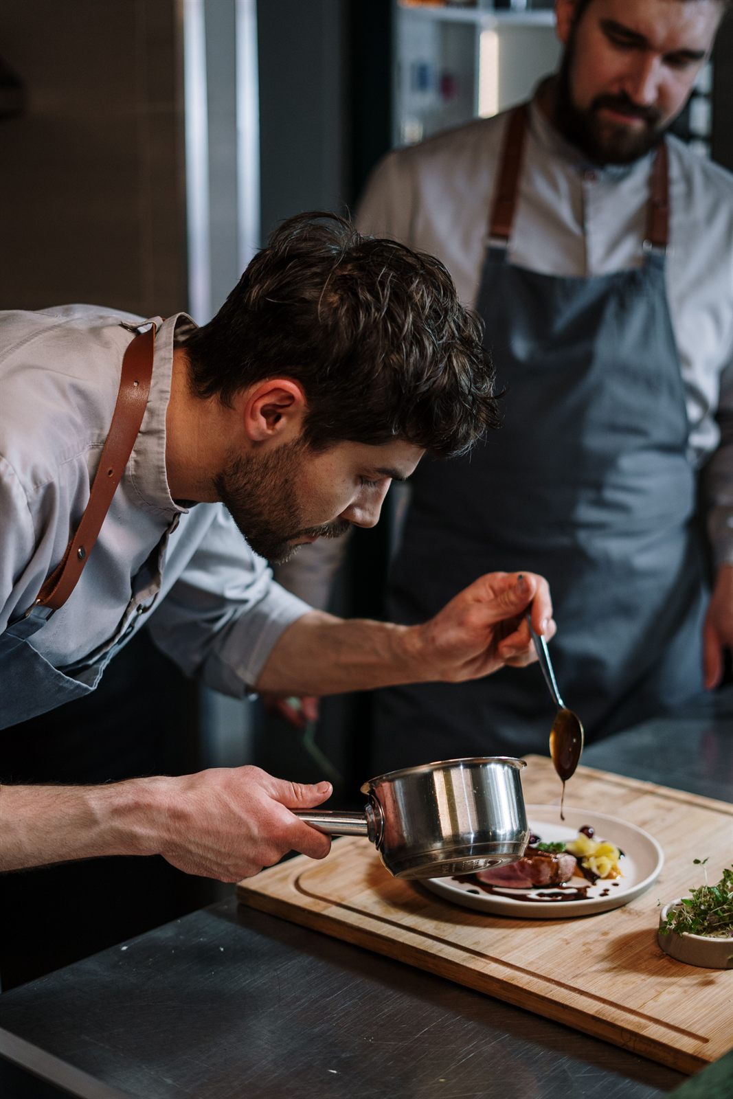 Le chef Julien Vasseur nappant une viande de sauce à la cuillère lors du dressage