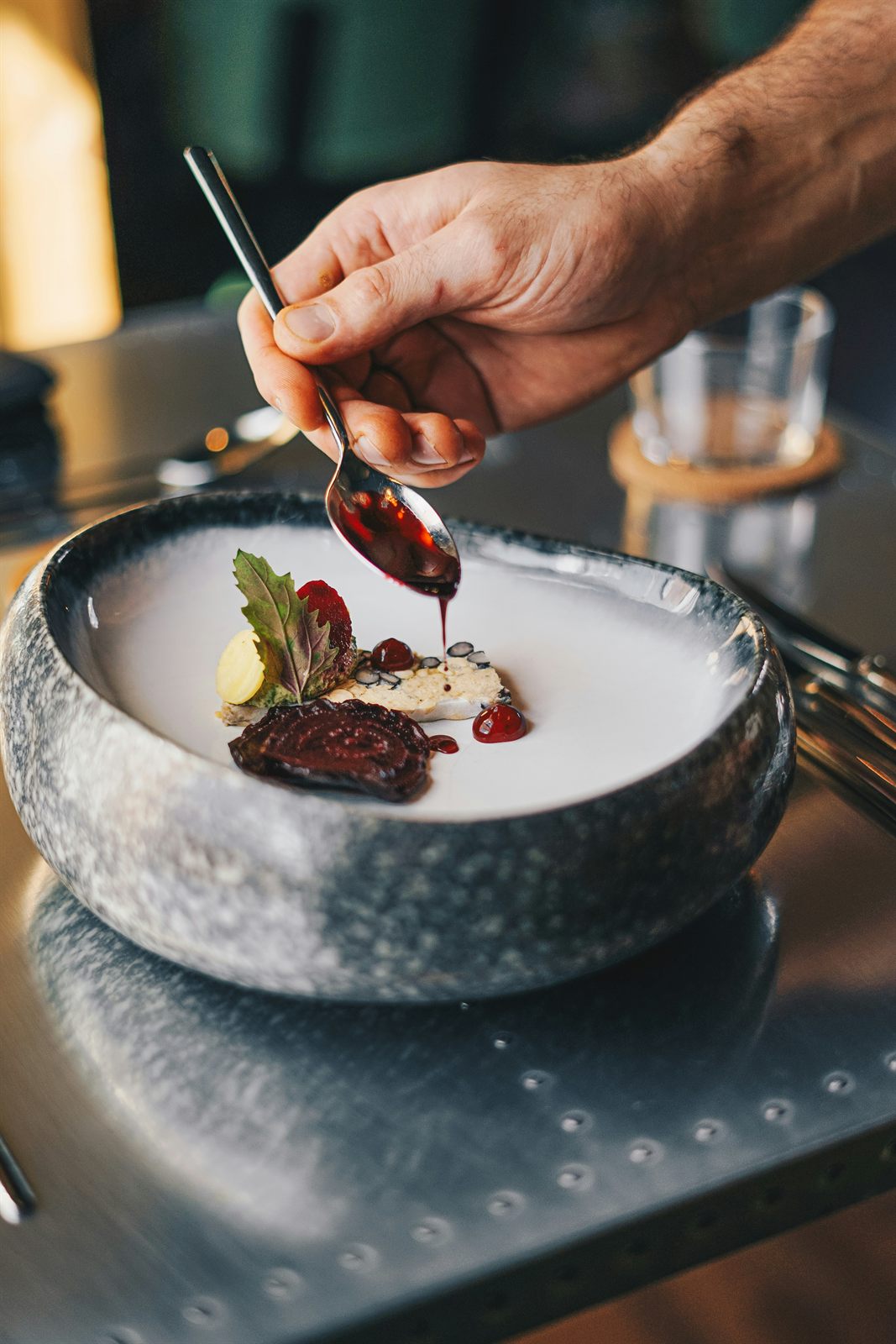 Dessert de saison dressé dans un bol en grès, nappé d'un coulis de fruits rouges